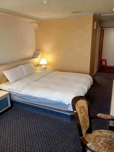 a hotel room with a large bed and a chair at Chungli Business Hotel in Zhongli