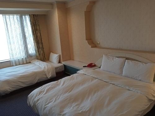 a hotel room with two beds and a window at Chungli Business Hotel in Zhongli