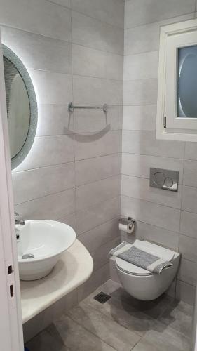 a bathroom with a sink and a toilet and a mirror at Augusta Studios & Apartments in Naousa