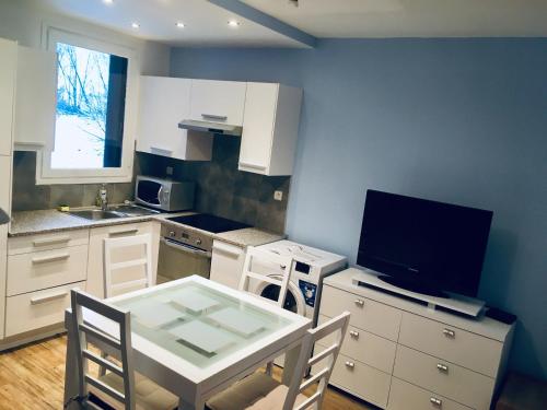 una cocina con mesa y TV. en Agréable studio neuf avec vue + parking gratuit, en Luchon