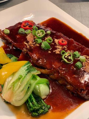 a plate of food with meat with sauce and broccoli at Siam cottage guesthouse over 300 years old with Thai restaurant in Moreton in Marsh