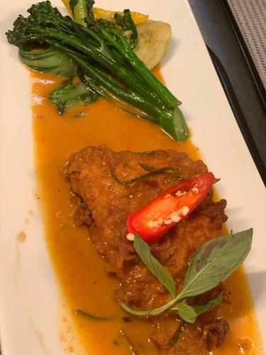 a plate of food with a piece of meat and vegetables at Siam cottage guesthouse over 300 years old with Thai restaurant in Moreton in Marsh