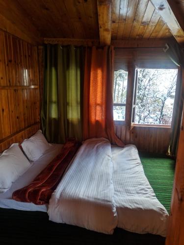 a large bed in a room with a window at Rustic wood house - A village home stay in Jibhi Valley in Jibhi