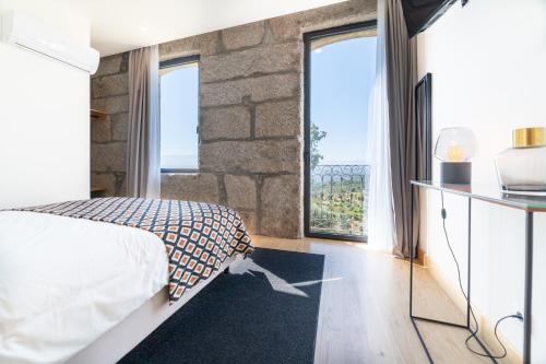 ein Schlafzimmer mit einem Bett und zwei großen Fenstern in der Unterkunft Casa Nova Rural in Nelas