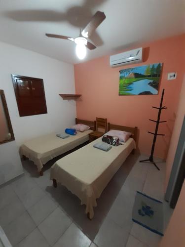 a room with two beds and a ceiling fan at Pousada dos Ventos in Pôrto de Pedras