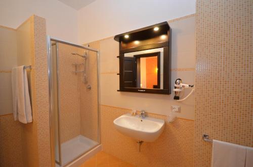 a bathroom with a sink and a shower and a mirror at Baia Santa Margherita B&B in Castelluzzo