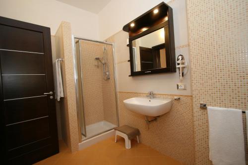 a bathroom with a sink and a shower and a mirror at Baia Santa Margherita B&B in Castelluzzo