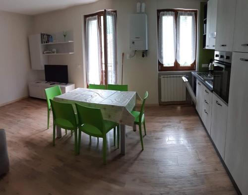 a kitchen with a table and green chairs in a room at Casa Ester in Serina