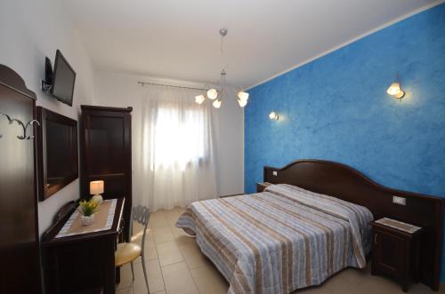 a bedroom with a bed and a blue wall at Baia Santa Margherita B&B in Castelluzzo