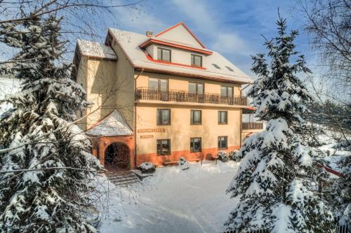 a large house in the snow with trees at Willa OdNova in Tylicz