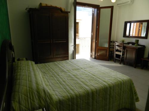 a bedroom with a bed with a green bedspread at Baia Santa Margherita B&B in Castelluzzo
