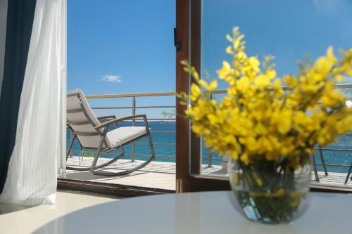 un vase de fleurs jaunes assis sur une table sur un balcon dans l'établissement Sunset Apartment Padrele, à Bibinje
