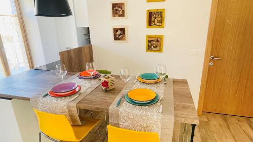 a dining room table with plates and wine glasses at La bougainville - luxury apartment in Nago-Torbole