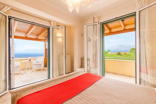 a bedroom with a large bed and large windows at Beachfront Villa Victoras - With private beach in Sidari