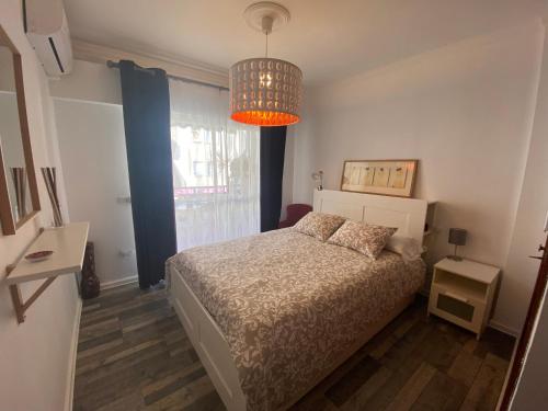 een slaapkamer met een bed en een kroonluchter bij Casa Ana in Sanlúcar de Barrameda