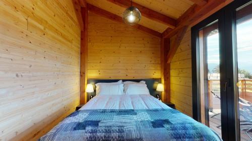 uma cama num quarto com paredes e janelas de madeira em Woodland Village Anzère em Ayent