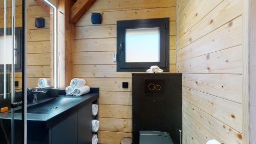 Ayent的住宿－Woodland Village Anzère，一间带水槽的浴室和墙上的电视