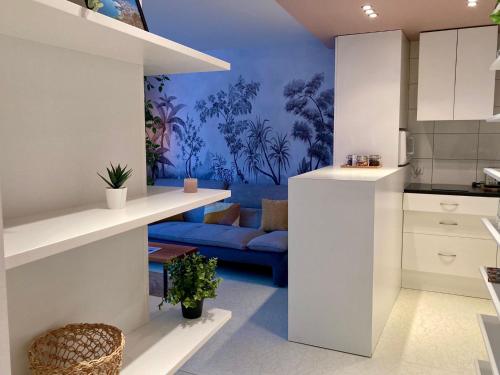 Il comprend une cuisine et un salon doté d'un canapé bleu. dans l'établissement LE LYS D'OR - cosy et proche lac, balcon terrasse, à Annecy