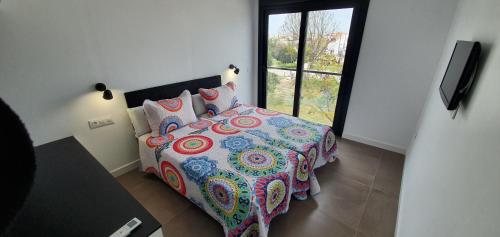 sypialnia z łóżkiem z kolorową kołdrą i oknem w obiekcie JOSE APARTAMENTo w mieście San Jose de la Rinconada