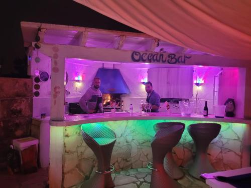 two men standing at a bar in a room with purple lights at Villa Ocean View in Portals Nous