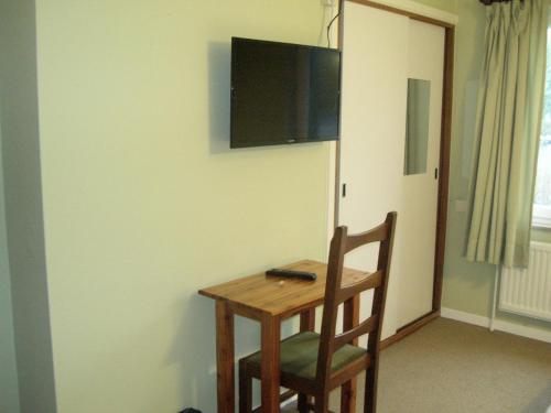 a wooden table and chair with a television on a wall at Auberge Le Vieux Moulin in Poupehan
