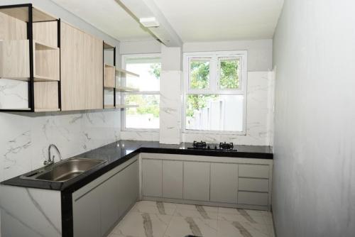 a white kitchen with a sink and a window at Villa Languket I in Bedoyo