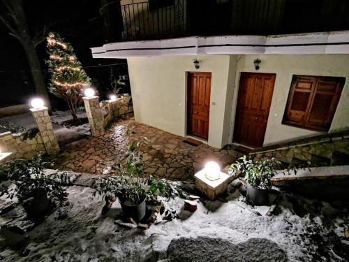 カラブリタにあるKERAMIDAKI MINI SUITES 4の雪の灯りと鉢植えの家
