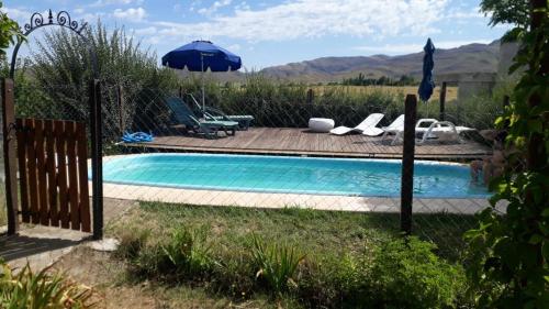 Una piscina en un patio con una sombrilla. en Cabañas Rincon de Campo San Andres De Las Sierras, en Villa Ventana