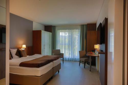 ein Hotelzimmer mit einem großen Bett und einem Schreibtisch in der Unterkunft Sporthotel TREFF PUNKT in Wiesbaden
