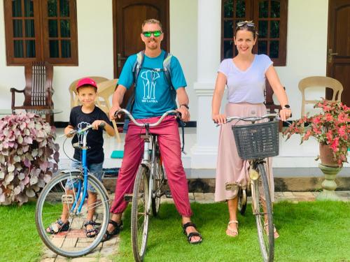 a family posing with their bikes in front of a house at Geethani Tourists Home in Polonnaruwa