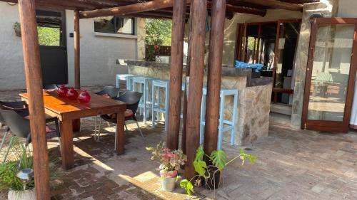 a patio with a wooden table and a stone fireplace at Ujabule Lodge in Hoedspruit