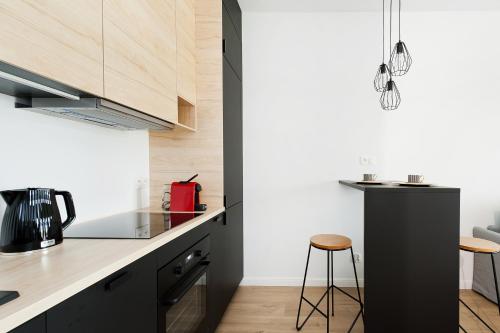 a kitchen with black cabinets and a counter with a stool at Central Apartments by Bed&Bath in Kraków