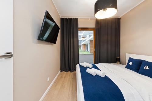 a bedroom with a bed with blue pillows and a tv at Central Apartments by Bed&Bath in Kraków