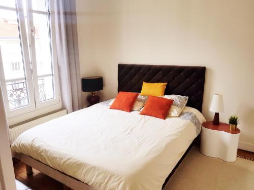 - une chambre dotée d'un grand lit avec des oreillers orange et jaune dans l'établissement Anna's Home Sweet Home, à Boulogne-Billancourt