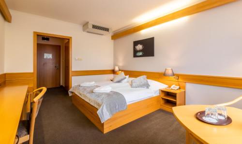 a bedroom with a bed and a desk and a table at Aqua Hotel Termál in Mosonmagyaróvár