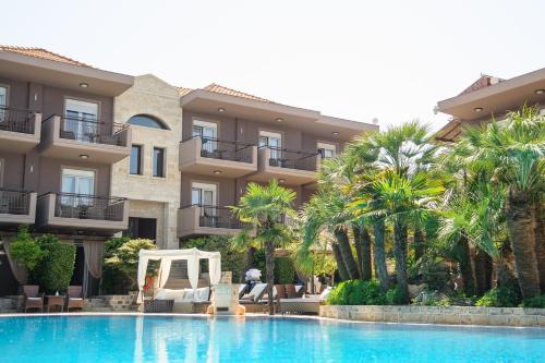 una piscina di fronte a un edificio con palme di Achtis Hotel ad Áfitos