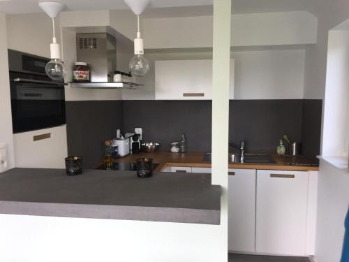 Una cocina con gabinetes blancos y encimera. en Le temps d’une balade., en Olne