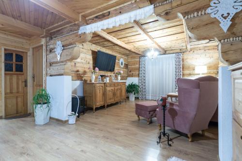 a living room with wooden walls and a tv and chairs at Chata Litwor in Bukowina Tatrzańska