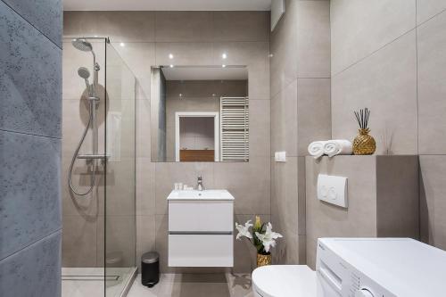 a bathroom with a shower and a toilet and a sink at Central Apartments by Bed&Bath in Kraków