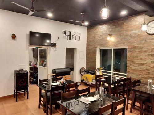 Heaven Valley Resorts Vagamon في فاغامون: غرفة طعام مع طاولات وكراسي وجدار من الطوب