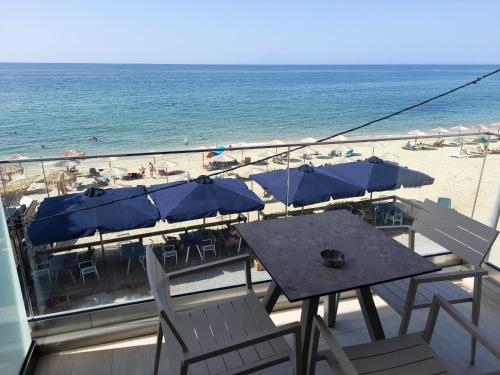 a balcony with a table and chairs and the beach at Reverie in Limenaria