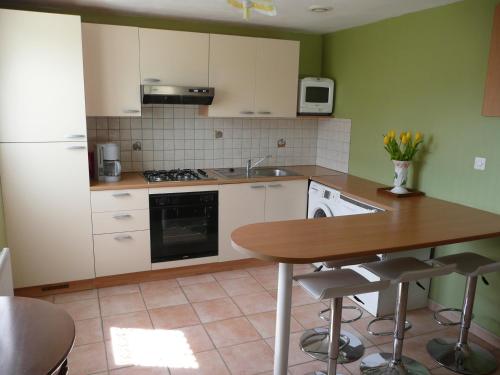 eine Küche mit weißen Schränken und einer hölzernen Arbeitsplatte in der Unterkunft Gîte berneval le grand in Berneval-le-Grand