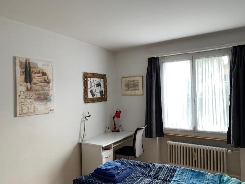 Schlafzimmer mit einem Bett, einem Schreibtisch und einem Fenster in der Unterkunft Wohnung in Bern