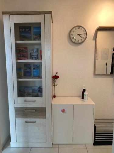 a white cabinet next to a wall with a clock at Wohnung in Bern