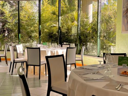 a restaurant with white tables and chairs and windows at Hotel Santacroce Meeting in Sulmona