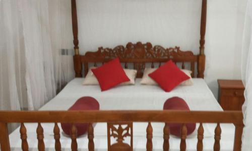 a bedroom with a bed with red pillows at Coral Reef Guest in Beruwala