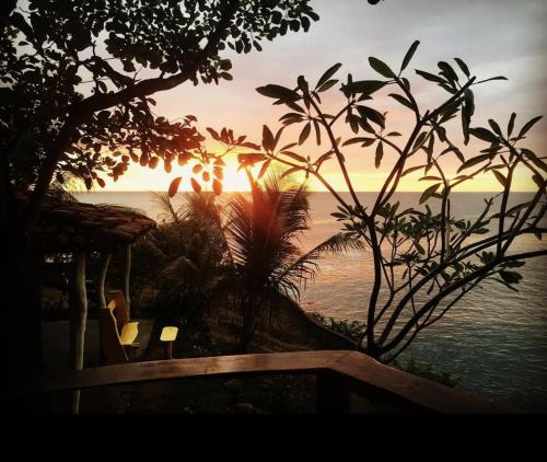 a sunset from a resort with the ocean in the background at Monkey House Hostel in Tola