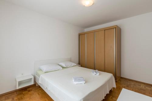 a white bedroom with a bed and a cabinet at Pujanke Residence - large 3 bedroom apartment in Split
