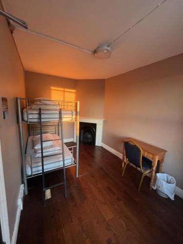 a room with bunk beds and a table and a desk at Queen Elizabeth Hostel in London