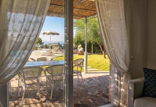 a glass door leading to a patio with a table and chairs at Villa dei Lecci - 7 Luxury villas with private pool or jacuzzi in Ischia